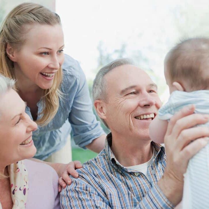 A man holds a baby while two women look on.